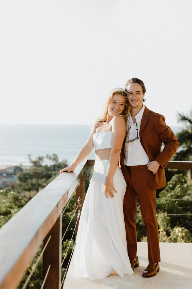 Katie and Justin embrace, surrounded by tropical paradise